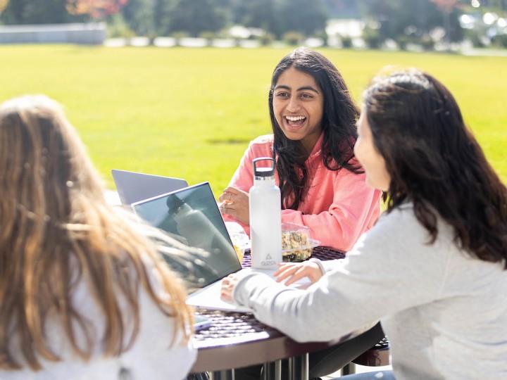 A group of students sit together outside on ACPHS campus during a beautiful sunny fall day